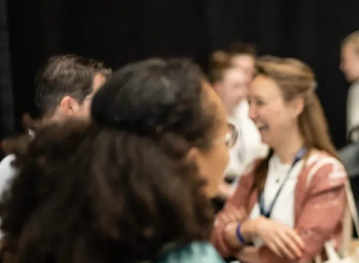 Two attendees laughing together in conversation