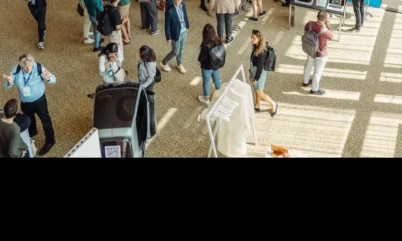 Visitors crossing a sunlit start-up exhibition floor, seen from above